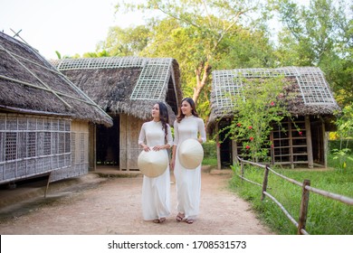 Two Vietnamese girls wearing a white Ao Dai and holding a conical hat at Hoang Tru, Kim Lien, Nam Dan. The Ao dai ( long-dress Vietnamese) is traditional costume of Vietnamese woman
