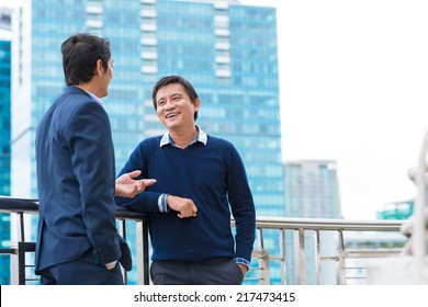 Two Vietnamese Male Coworkers Talking And Smiling