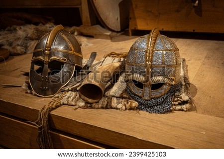 two viking helmets and a drinking horne on a wooden table, Lejre, Denmark, December 10, 2023