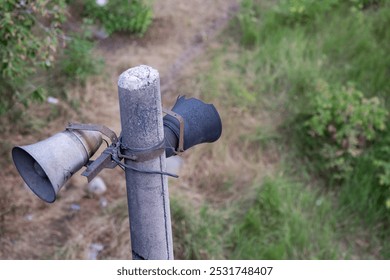 two vintage loudspeakers, one charred and abandoned on a concrete pole, symbolizing decay and nostalgia. It reflects the passage of time and forgotten technology - Powered by Shutterstock