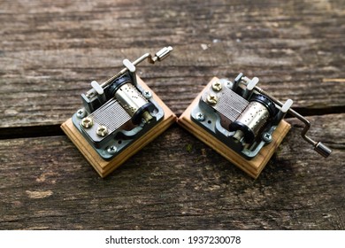 Two Vintage Mechanical Souvenir Music Box On Aged, Weathered Pine Wood Boards.