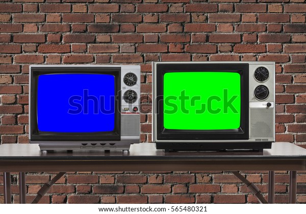 Two vintage televisions with brick wall and\
chroma key blue and green\
screens.