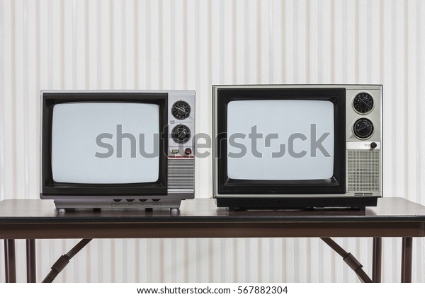 Two vintage televisions on\
table.