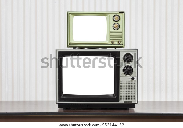 Two vintage televisions stacked on table with\
cut out screens.