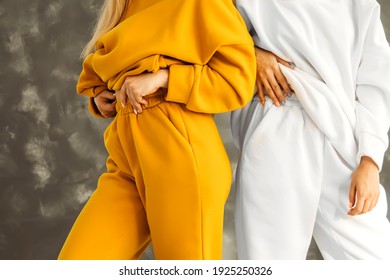 Two waist girls in warm tracksuits on white and mustard-colored fleece on a gray background