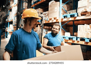 Two warehouse workers carrying boxes in distribution center
