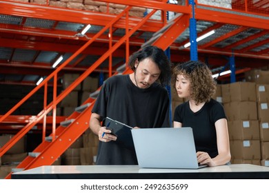 Two warehouse workers collaborating on a laptop, discussing inventory and logistics in a modern warehouse environment. - Powered by Shutterstock