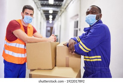 Two Warehouse Workers With Face Masks Because Of Covid-19 With Packages In The Warehouse