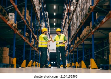 Two warehouse workers having bro handshake and smiling at each other. - Shutterstock ID 2134153593