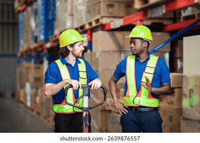 Two warehouse workers push a loaded cart while discussing tasks and pointing directions, showing teamwork in logistics operations.
