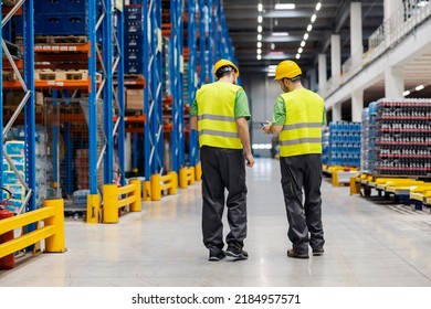 Two Warehouse Workers Talking And Looking At The Tablet In Facility.