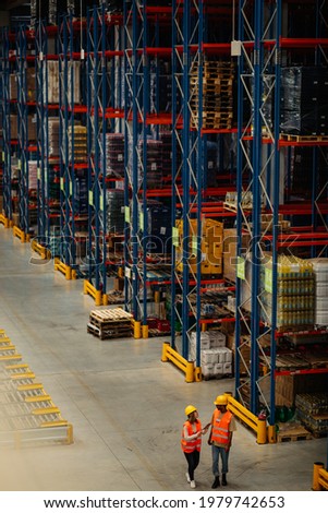 Two warehouse workers walking between shelves and having conversation