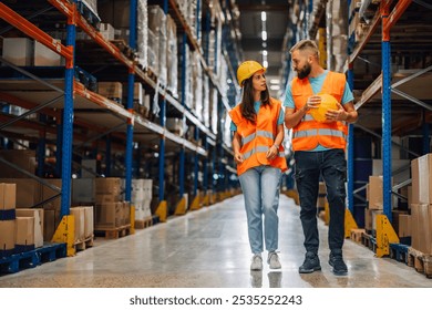 Two warehouse workers walking and talking in aisle filled with boxes, showcasing teamwork and communication in fast paced industry setting - Powered by Shutterstock