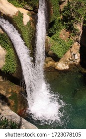 Two waterfalls meet as they flow downstream in a clean pond in natural canyon