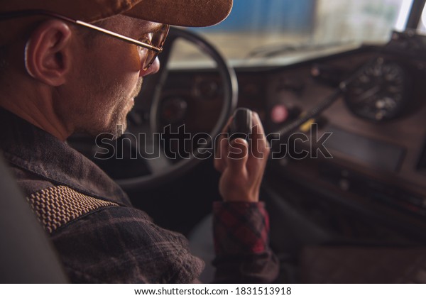 Two Way CB Radio\
Convoy Communication. Caucasian Trucker in His 40s Making\
Conversation Using Built In Truck Cabin Radio. Transportation and\
Communication Theme.