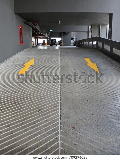 Two way Yellow Arrow signs on slope floor at\
park building.