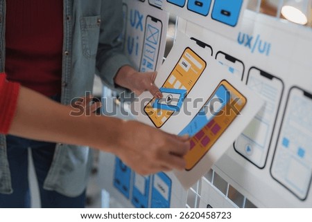 Two web designers collaborating on a project, reviewing and discussing different layouts and functionalities for a mobile application's user interface and user experience