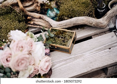 Two Wedding Dress With A Mirrored Jewelry Box On Wooden Boards With A Bouquet Of Pink Roses And Driftwood.