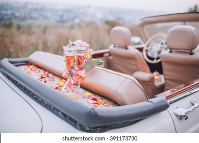 Two wedding glasses and bridal bouquet on retro car in autumn park