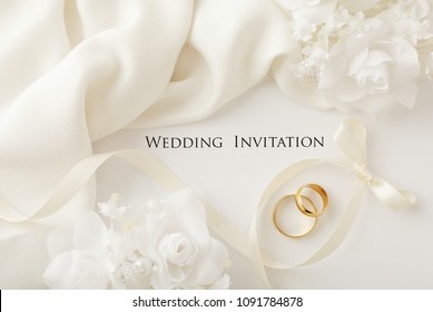 two wedding rings and wedding invitation