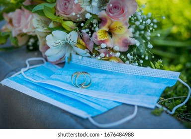 Two wedding rings lie on medical masks on the background of a wedding bouquet. Quarantine Wedding, Coronovirus - Powered by Shutterstock