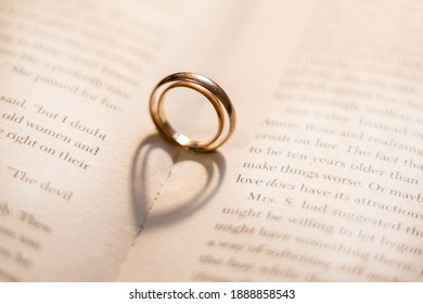 Two wedding rings on the book cast shadows in the form of hearts. Valentine's Day. Romance. - Powered by Shutterstock