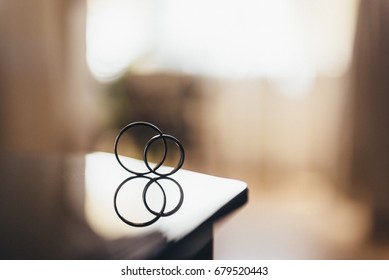 Two wedding rings with reflection on a mirror table