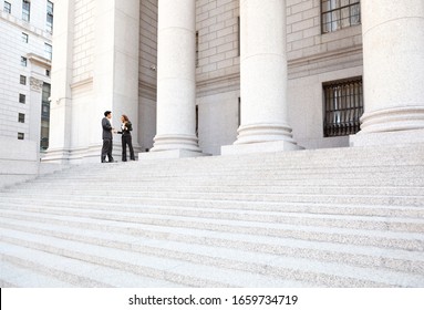 Two well dressed professionals in discussion on the exterior steps of a courthouse. Could be lawyers, business people etc. - Shutterstock ID 1659734719