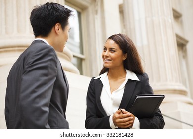 Two Well Dressed Professionals In Discussion Outdoors In Front Of A Courthouse Or Government Building. Could Be Lawyers, Business People Etc.