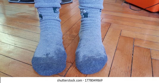 Two wet feet in grey socks on a wooden parquet floor at home