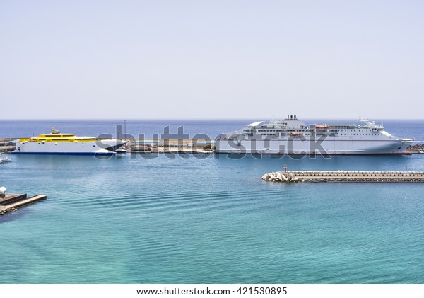 Two white auto\
ferries lying at a pier in the turquoise Atlantic sea on the Canary\
islands waiting to be\
loaded.