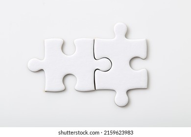 Two white blank puzzle pieces on a white background Merging different elements into a whole
