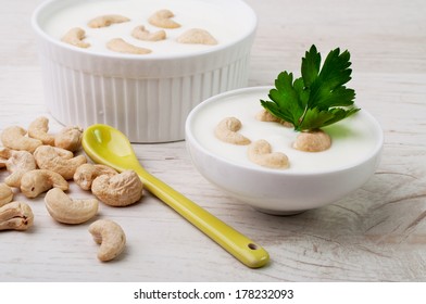 Two White Bowls With Cashew Nuts And White Cream Sauce