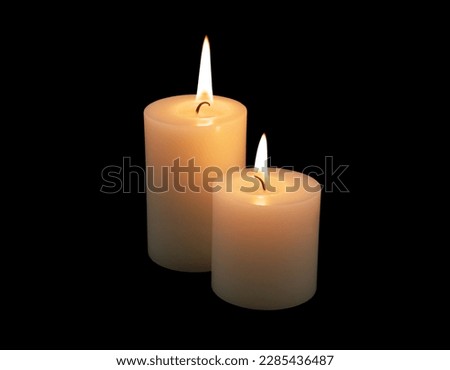 Two white burning candles isolated on black.