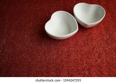 two white ceramic bowls in the shape of a heart on a red background with sparkles for a festive romantic design for a wedding, Valentine's Day, birthday greetings, copy space - Powered by Shutterstock