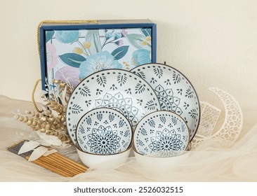 two white ceramic plate with ethnic motif, bowl, and chopstick on a white background, Ramadan theme background, plant and green fabric - Powered by Shutterstock