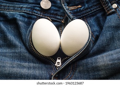 Two white chicken eggs on jeans as a symbol of male testicle.