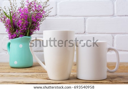 Two white coffee and cappuccino mug mockup with maroon purple field flowers in polka dot mint green pitcher vase.  Empty mug mock up for design promotion.   