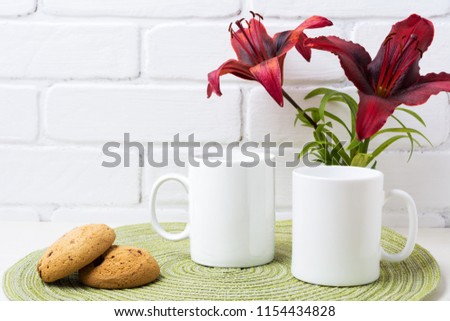 Two white coffee  mug mockup with dark burgundy lily and cookie.  Empty mug mock up for design promotion.   
