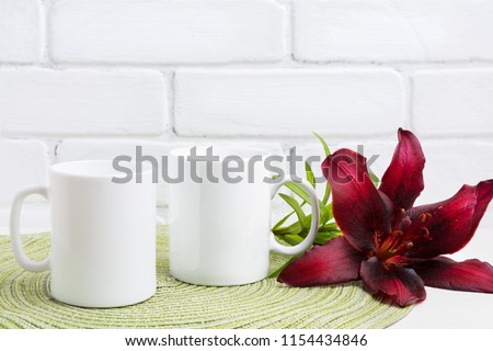 Two white coffee mug mockup with dark burgundy lily.  Empty mug mock up for design promotion.   