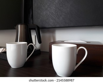 Two white cups and a teapot are placed on the table