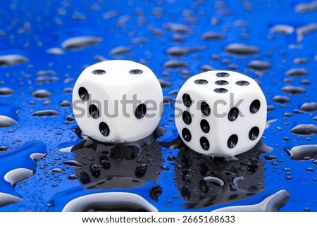 Two white dice with black dots on a blue background with water drops