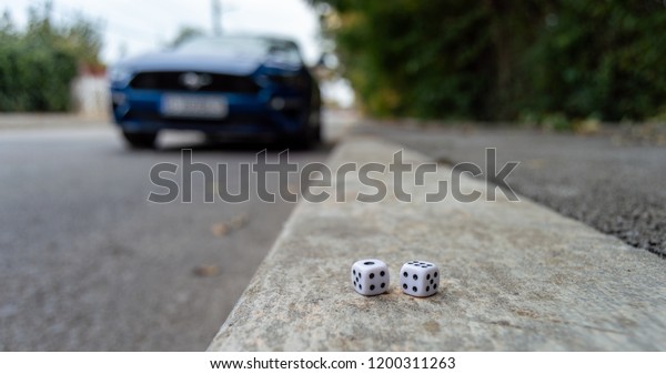 Two white dice in front of a\
car