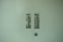 Two White Doors With Metallic Pull Sign And Door Knob In Metallic Style.                             