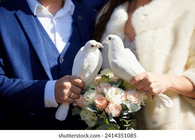 Two white doves in the hands of the bride and groom. It is a wedding tradition to release birds into the sky. A wedding or engagement. - Powered by Shutterstock