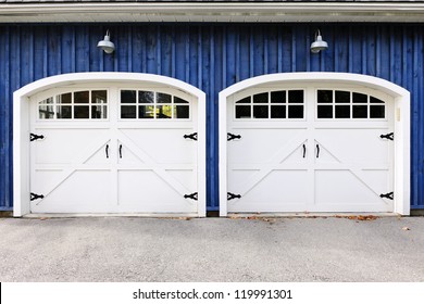 Two White Garage Doors With Windows On Blue House