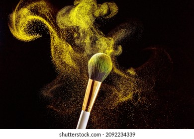 Two white with gold makeup brushes on a black background. Powder brush, fine powder particles around.