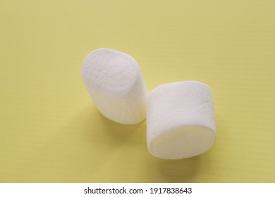two white marshmallows in the yellow background