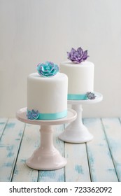 Two White Mini Wedding Cakes Covererd With Fondant With Gum Paste Succulents On Cake Stands