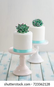 Two White Mini Wedding Cakes Covererd With Fondant With Gum Paste Succulents On Cake Stands